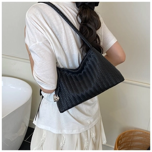 Detail of black woven hobo bag featuring a silver heart pendant and rope shoulder strap