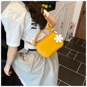 Detailed view of bright yellow litchi texture bag with a 3D white flower charm and strap