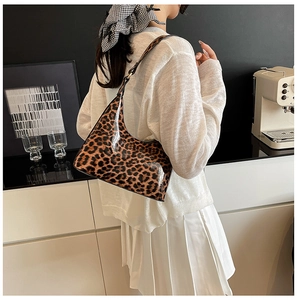 Fashionable leopard print hobo bag worn by a model in a cozy, modern cafe setting