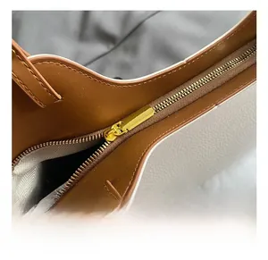 Detailed close-up of a white leather tote bag with gold metal zipper and brown trim