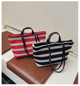Gros plan de sacs cabas en tricot rayé rouge, noir et blanc avec poignées en cuir
