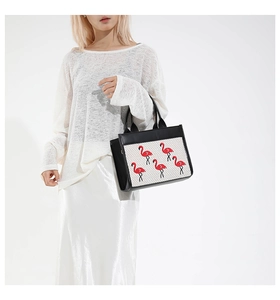 Détail d'un sac cabas chic avec broderie flamant rose sur une texture tissée élégante