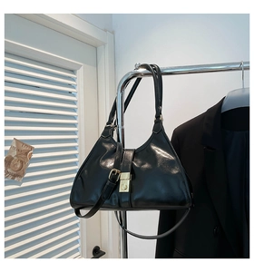 Gros plan détaillé du sac sous le bras en cuir verni noir avec boucle en métal doré