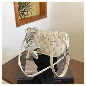 Detail of quilted beige crossbody bag with silver star charm and rhinestone stud accents