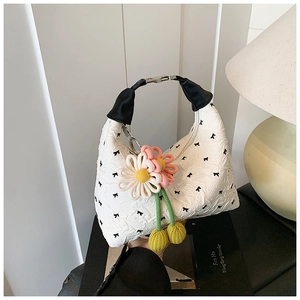 Detail der weißen Plissee-Hobo-Tasche mit gestickten schwarzen Schleifen und Blumenanhänger