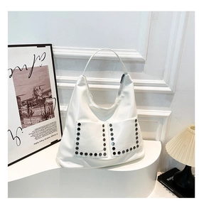 Detail of white glossy hobo bag featuring silver rivets and functional front pockets