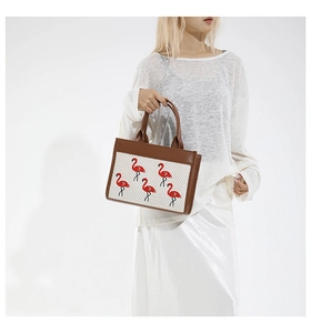 Détail du sac fourre-tout tissé blanc avec broderie de flamants roses et anses en cuir