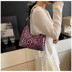 Glossy purple leopard print hobo bag worn by a model in a modern cafe setting