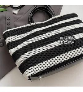 Détail de la texture d'un sac cabas en maille rayée avec poignée en cuir sur un costume