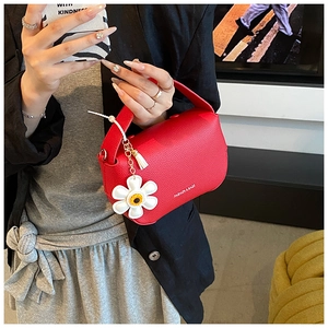 Close-up of red lychee pattern handbag with fashion logo and daisy flower charm detail