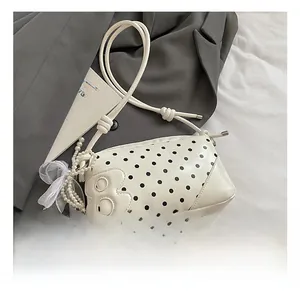 Detailed shot of white polka dot handbag featuring pearl charms and a bow accessory