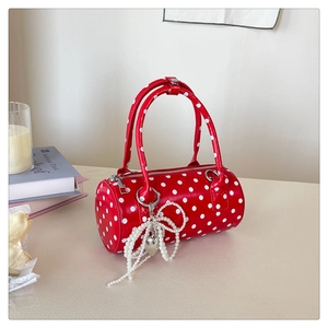 Vue détaillée du sac polochon rouge à pois avec pendentif perle sur une table