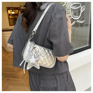 Detail of silver metallic quilted half moon bag with large star and butterfly charms