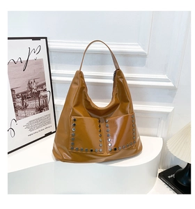 Detail of vintage caramel PU leather hobo bag featuring silver hexagonal rivet accents