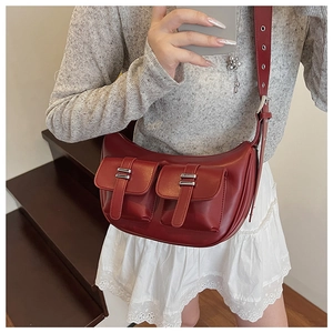 Detail of red crescent leather tote with multiple pockets and silver metal buckles
