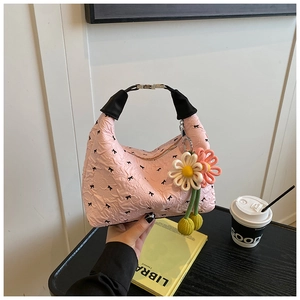 Detailaufnahme der rosa Handtasche mit Blasenstruktur, Schleifen und Blumenanhänger