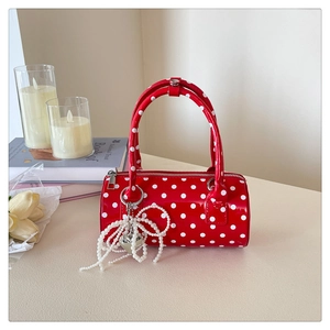 Détail du sac cylindre rouge à pois avec breloque cœur perle et finition brillante