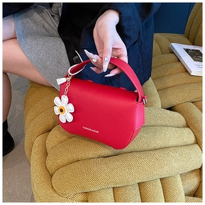 Close-up of red lychee grain leather bag with a white daisy floral charm detail