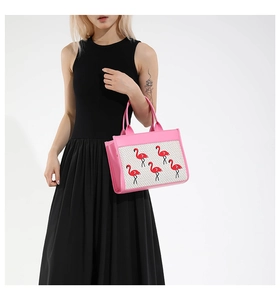 Vue détaillée du sac à main en cuir rose avec broderie flamant porté par un mannequin