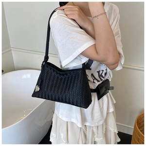 Detail of black woven hobo bag with heart charm and matching leather waist accessory