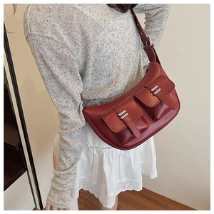 Detail of dark red faux leather crescent bag with functional pockets and silver hardware