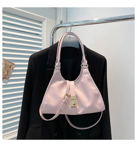 Sac trapèze rose en similicuir avec boucle dorée présenté sur une veste de tailleur