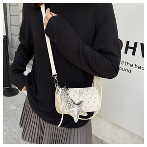 Close-up of cream quilted crossbody bag with silver star charms and patent leather finish