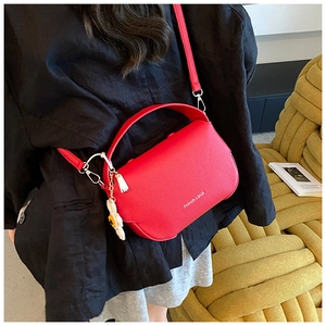 Detail of red lychee texture crossbody bag with fashion text and daisy pendant