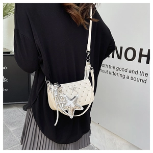 Detail of beige quilted crossbody bag featuring a large silver sequin star charm