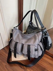 Chic large grey tote bag with black wide strap and multi-pocket design on wood floor