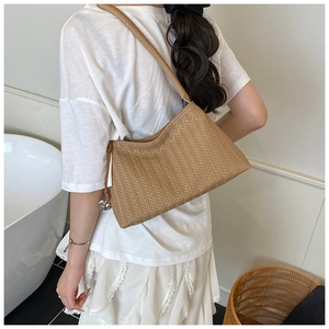Detail of woven tan hobo bag with herringbone pattern and heart-shaped metal pendant
