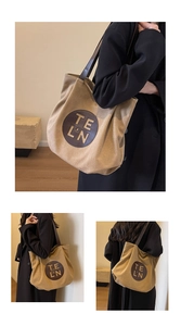 Close-up of khaki canvas tote bag featuring a leather logo patch and premium brown straps
