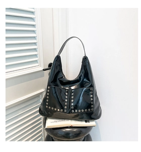Close-up of black glossy hobo bag with silver rivets and functional front pockets