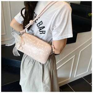 Gros plan du sac carré rose à pois avec nœud en dentelle et breloque en perles