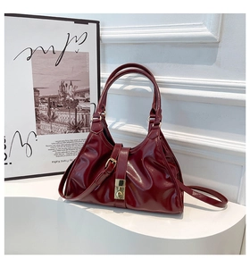 Détail du sac sous le bras en cuir verni bordeaux avec texture plissée et fermoir métal