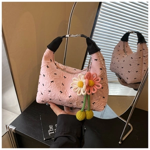 Rosafarbene Falten-Tasche mit schwarzen Schleifen und floralem Anhänger im Detail