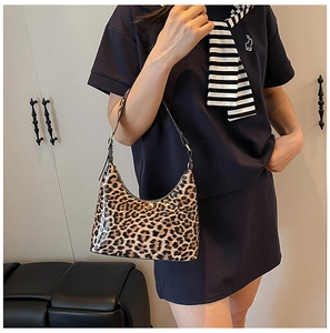 Detail of trendy leopard print shoulder bag worn by model featuring glossy finish