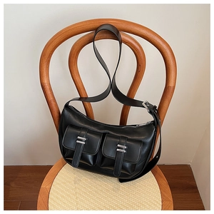 Macro shot of black vintage PU leather underarm bag with silver buckles on a wooden chair