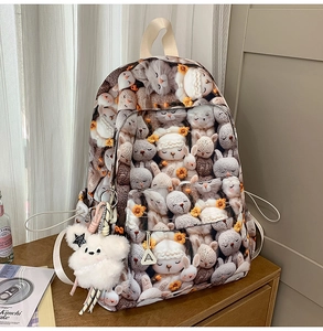 Close-up of canvas backpack featuring cartoon animal prints and a plush bear pendant