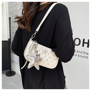 Close-up of cream quilted crossbody bag with rhinestone star detail and silver charm