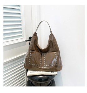 Macro shot of silver hexagonal rivets on deep brown glossy faux leather tote bag