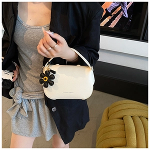 Close-up of white lychee pattern leather handbag with a black sunflower charm accessory