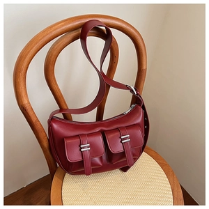 Detail of dark red leather crescent bag with double front pockets and silver hardware