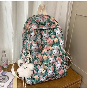 Detail of green backpack with white bunny and pink rose print plus star plush charm