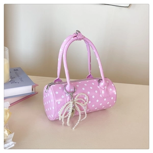Détail de sac cylindrique rose à pois avec un élégant pendentif nœud en perles nacrées