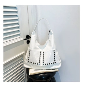 Detail view of a white faux leather hobo bag with silver hexagonal rivets and front pockets