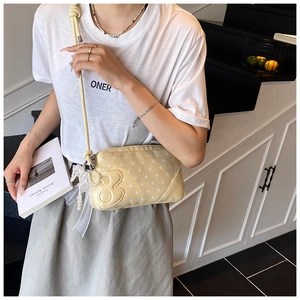 Détail d'un sac bandoulière jaune à pois avec breloque en perles et nœud en résille