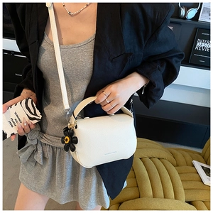 Chic cream leather handbag with lychee texture and black sunflower charm in a street style