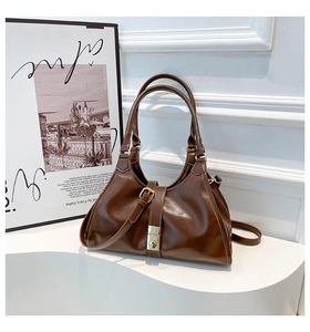 Gros plan du sac sous le bras en cuir brillant marron avec boucle en métal doré