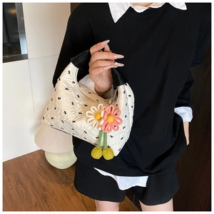 Detailansicht der weißen strukturierten Hobo-Tasche mit schwarzen Schleifen und Blumenanhänger